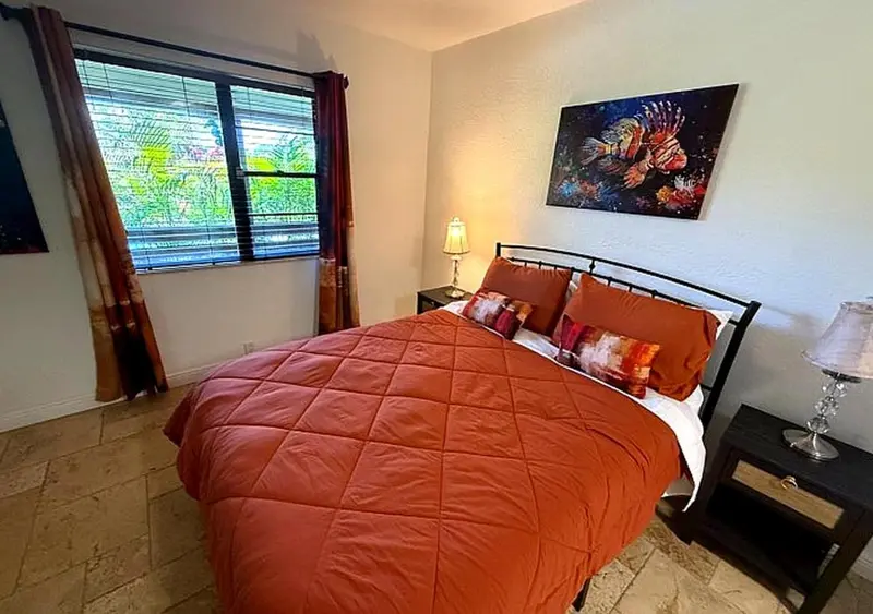 Une chambre à coucher avec un lit recouvert d'une courtepointe orange et une fenêtre.