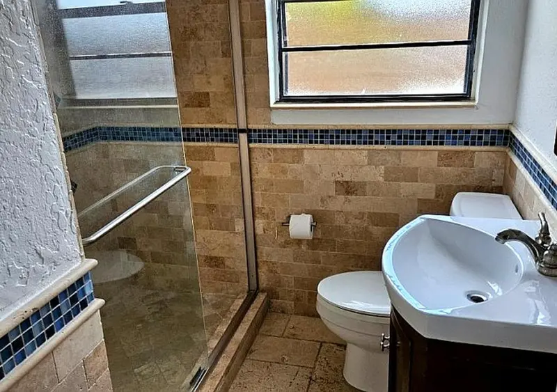 Une salle de bain carrelée avec douche à l'italienne et lavabo.
