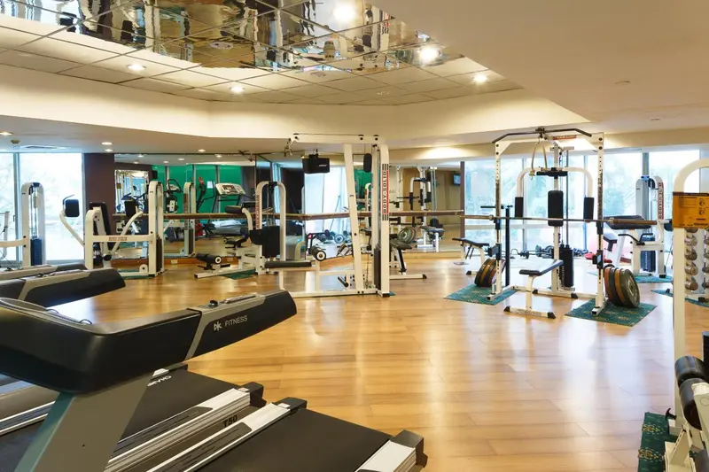 Une salle de sport lumineuse avec des équipements de musculation et des tapis de course.