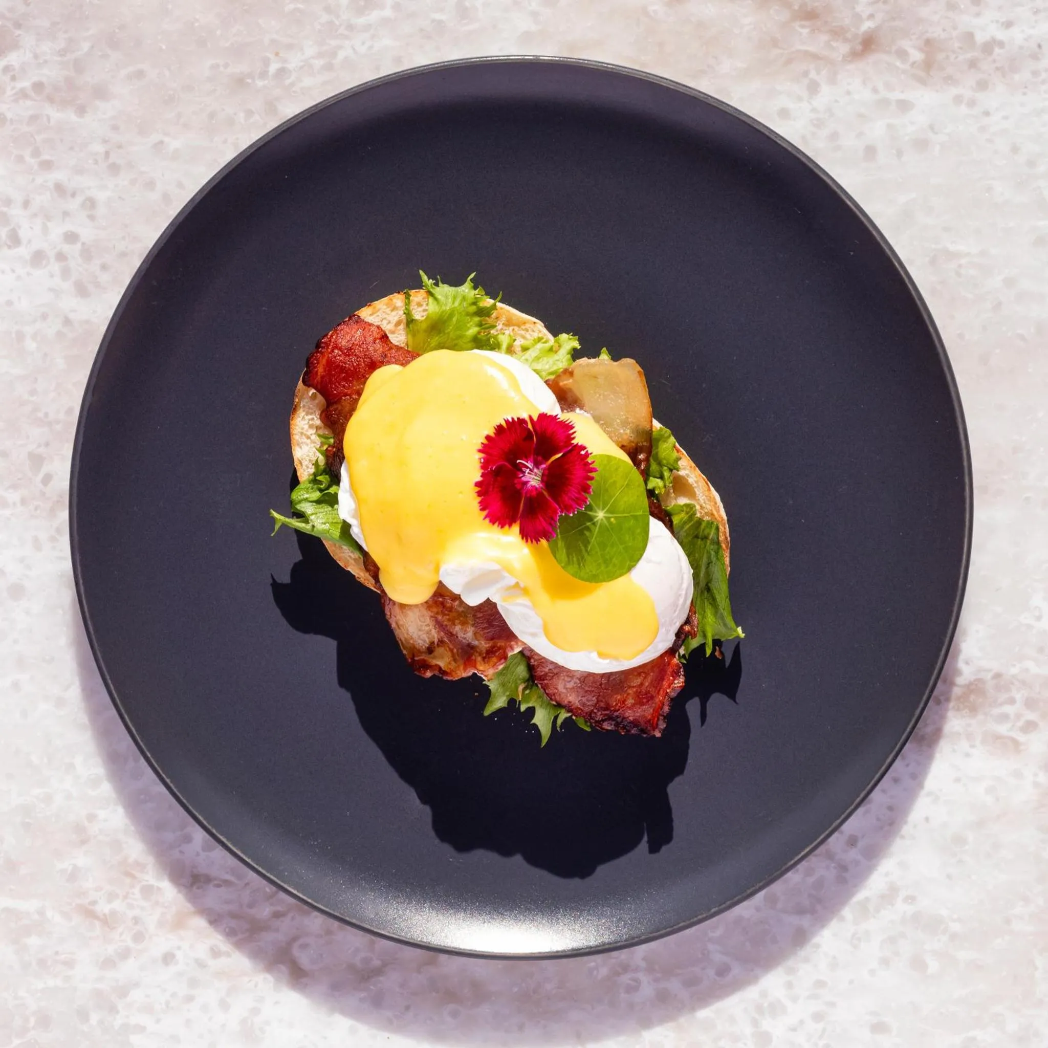 Assiette présentée avec un plat composé d'œufs pochés, de bacon et de verdure.