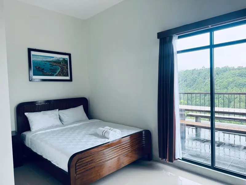 Une chambre lumineuse avec un lit et une vue sur la végétation.