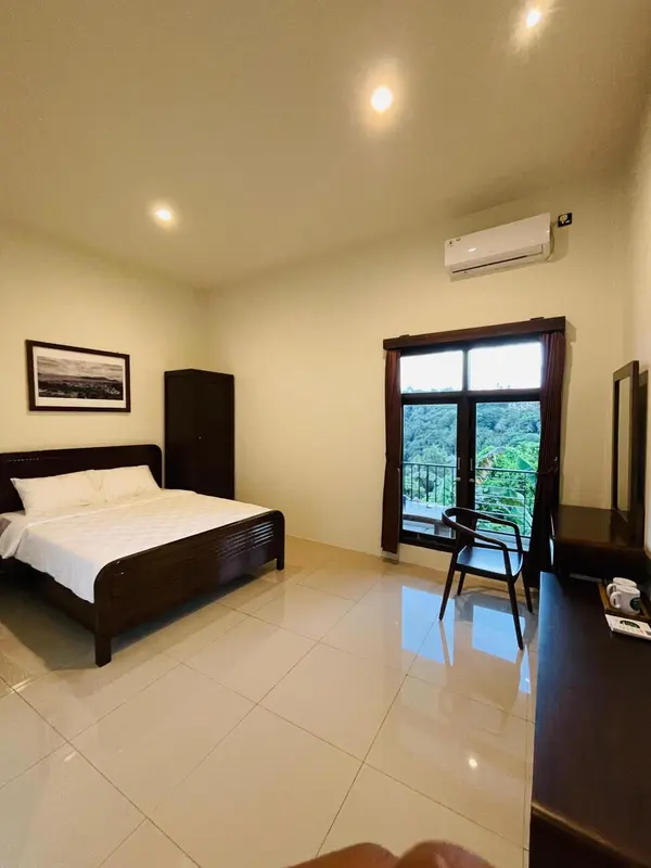 Une chambre lumineuse avec un lit simple et une vue sur la végétation.