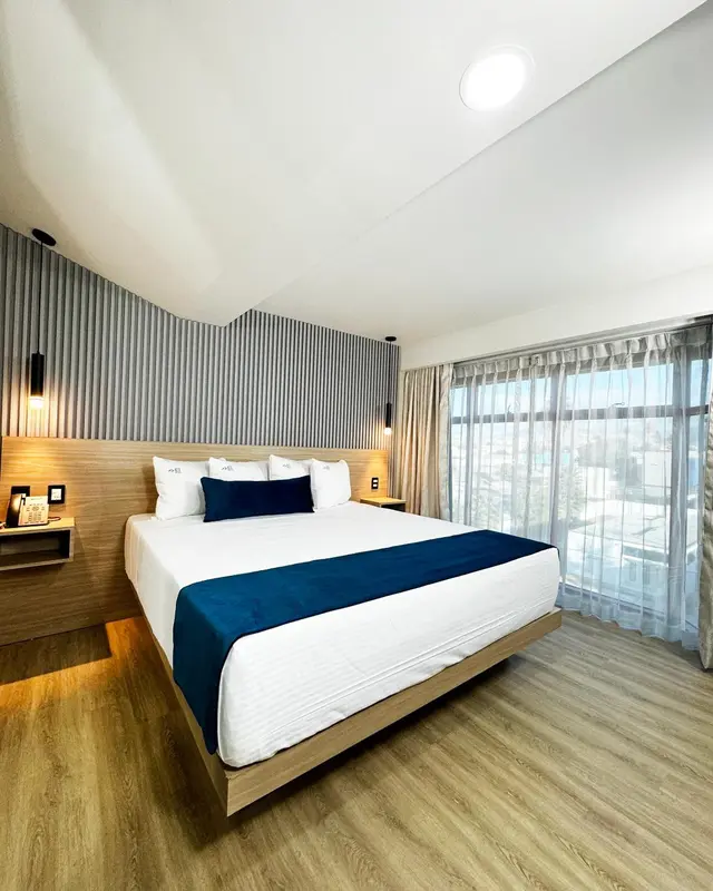 Une chambre avec un grand lit recouvert d'une courtepointe bleue et de coussins blancs.