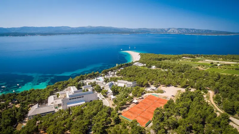 Vue aérienne d'un complexe hôtelier bordant une plage de sable fin et une mer turquoise.