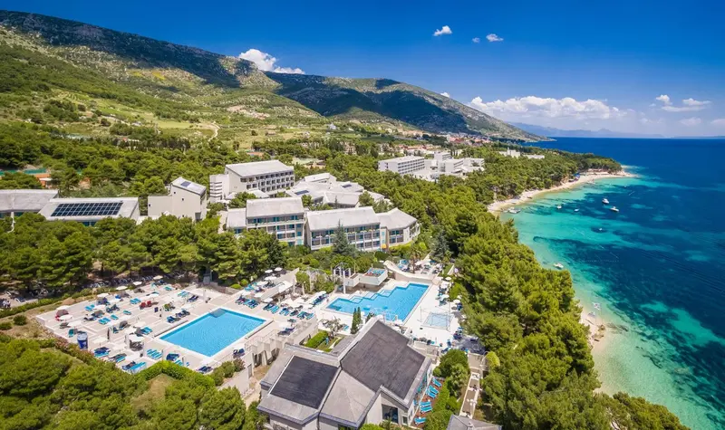 Vue aérienne d'un complexe hôtelier bordant une plage de sable fin et une mer turquoise.