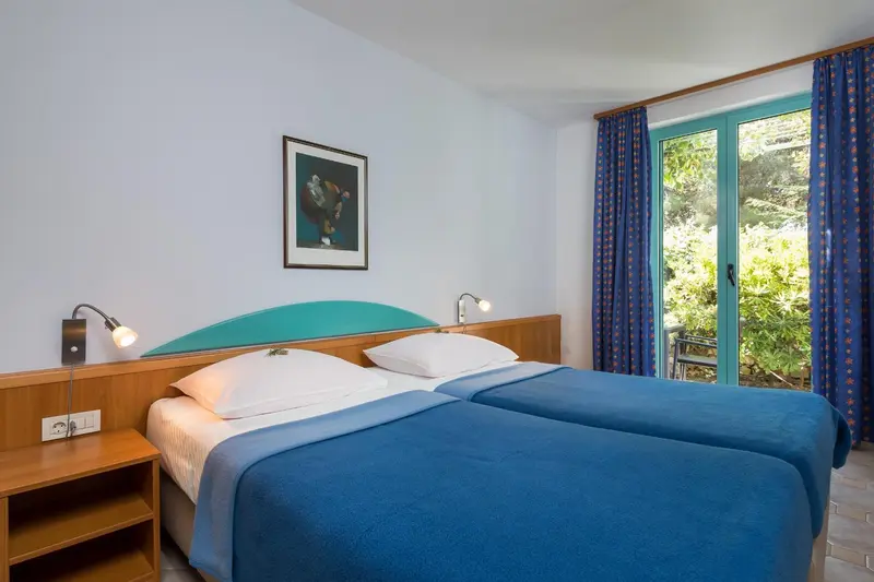 Une chambre lumineuse avec un grand lit et une porte-fenêtre donnant sur l'extérieur.