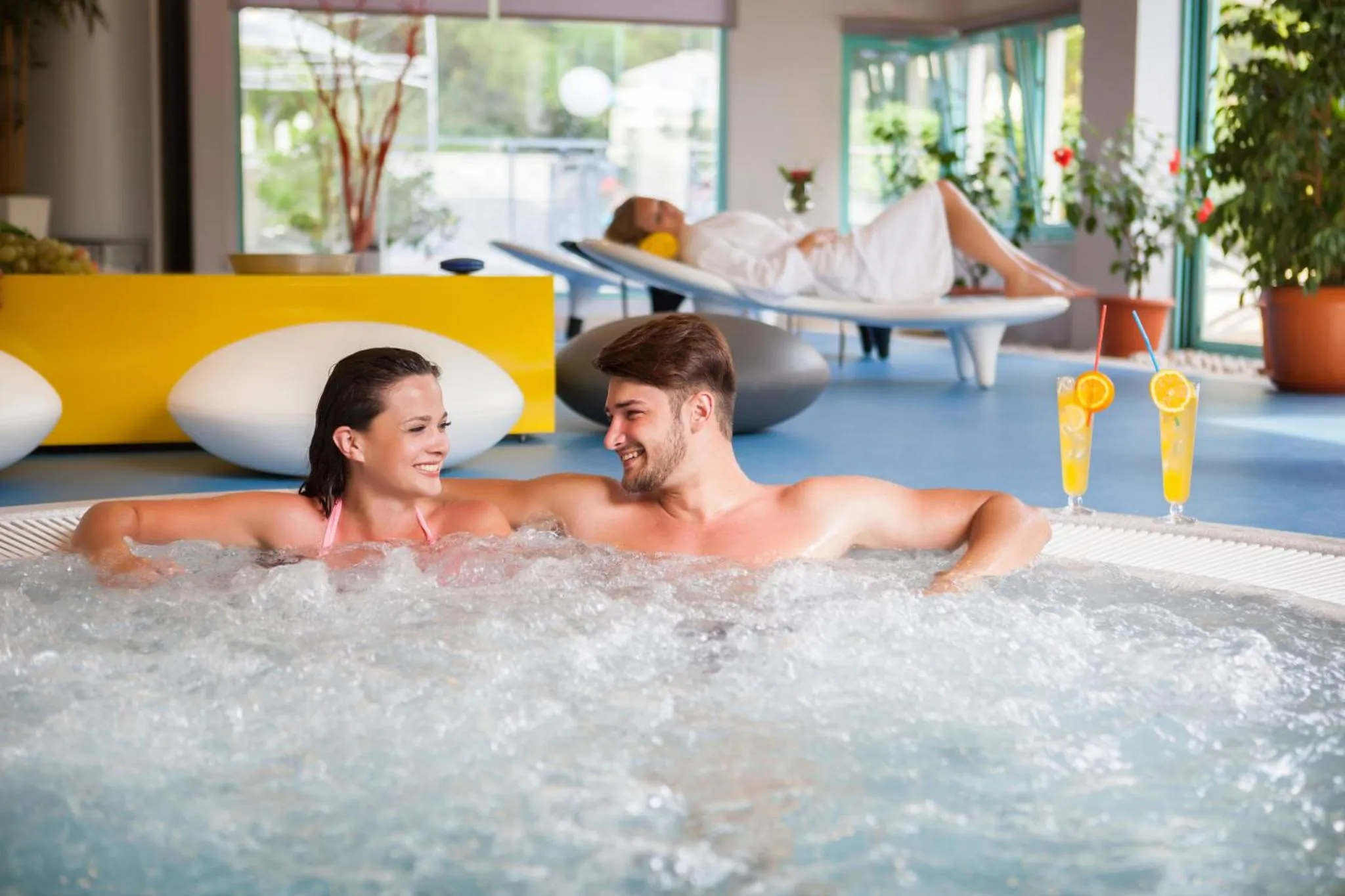 Un couple se détend dans un jacuzzi avec des boissons colorées.
