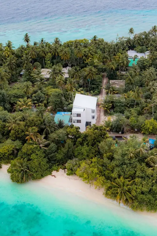 Vue aérienne d'une île tropicale avec une plage de sable blanc et une végétation luxuriante.