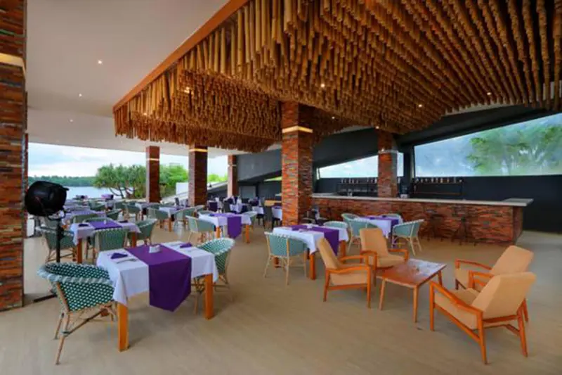 Une salle à manger extérieure avec des tables dressées et un bar en fond.