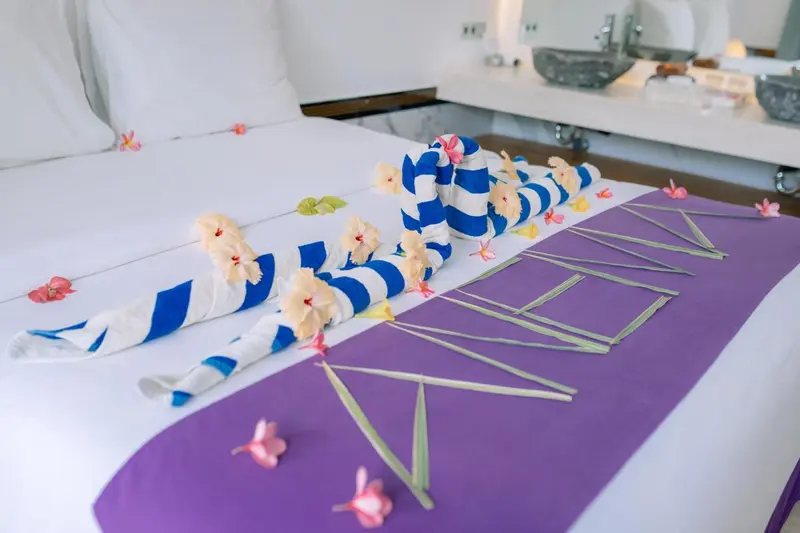 Lit décoré de fleurs et serviettes colorées dans une chambre.