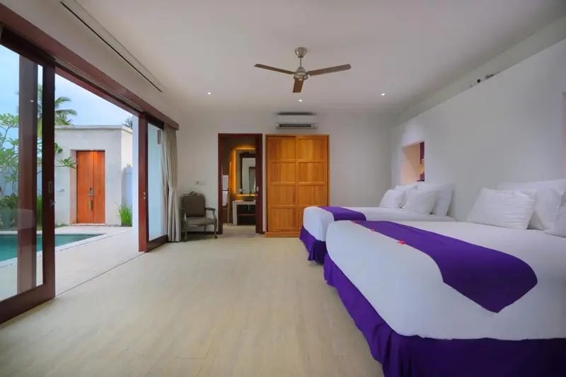 Une chambre lumineuse avec deux lits et un accès à une piscine.