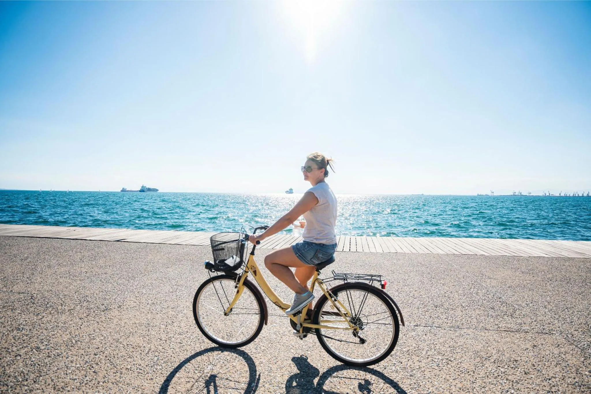 Une personne à vélo roule sur une promenade en bord de mer ensoleillé.