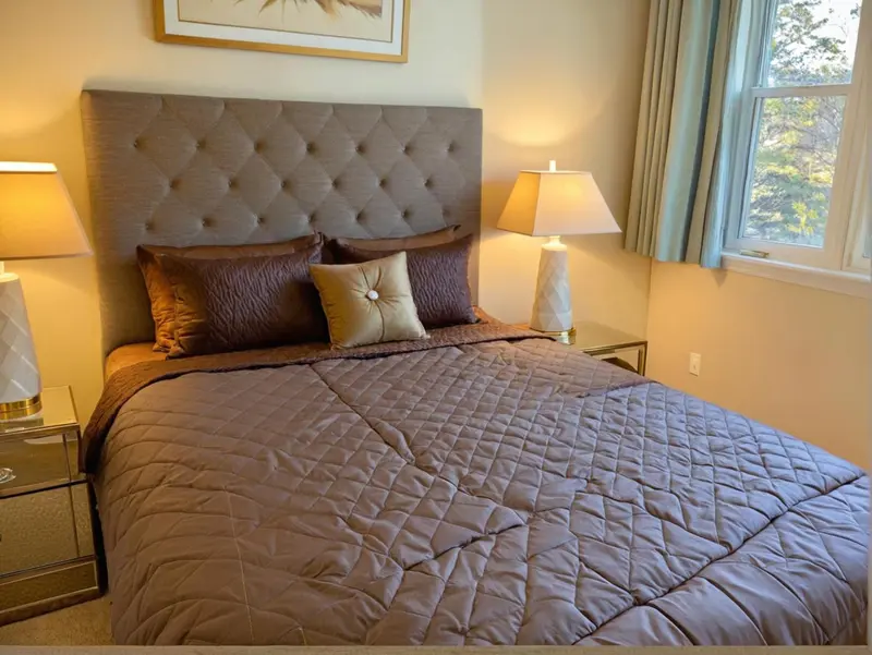 Une chambre avec un grand lit recouvert d'une courtepointe et de coussins.