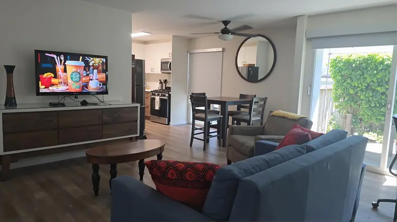 Interieur lumineux avec canape, table basse et cuisine ouverte.