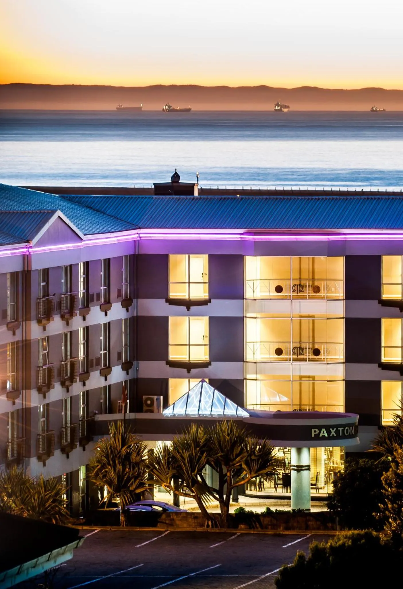 Bâtiment moderne éclairé au crépuscule avec vue sur la mer.