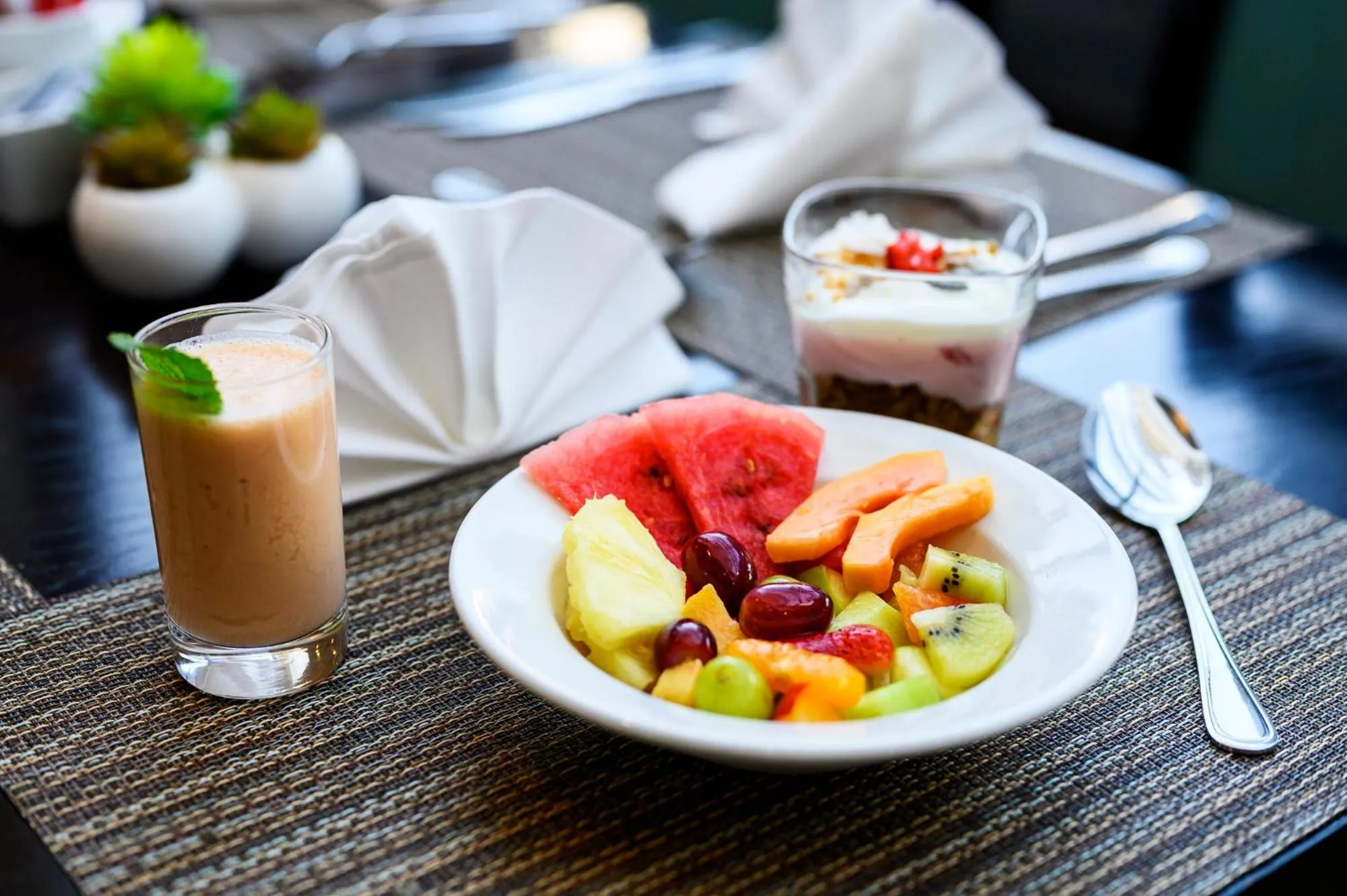 Assiette de fruits frais et boisson rafraîchissante sur une table.