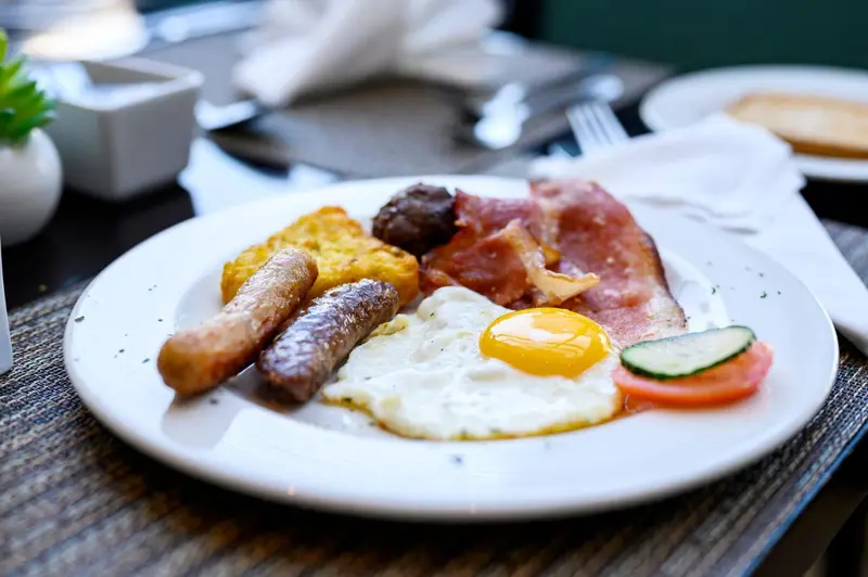 Assiette copieuse avec œufs, saucisses, bacon, galette de pommes de terre et accompagnements.
