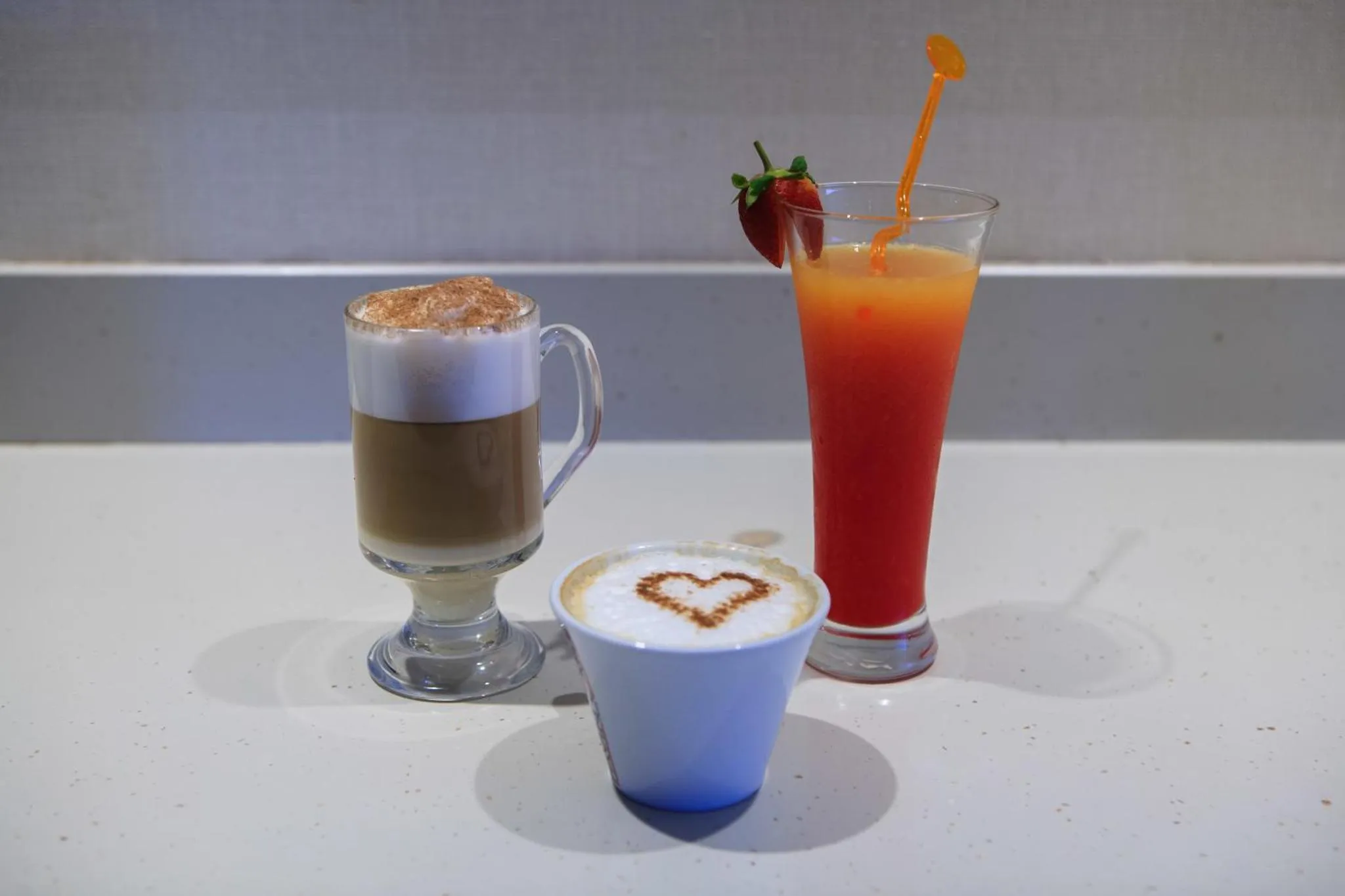 Trois boissons colorées sont présentées sur un comptoir blanc.