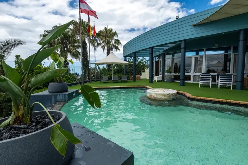Une piscine turquoise bordée de végétation luxuriante et de chaises longues.