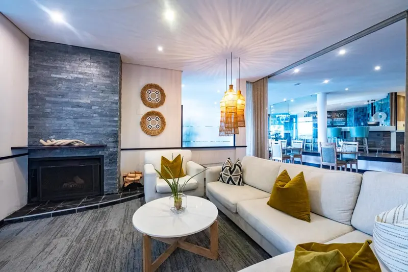 Un salon clair avec un canapé, des fauteuils et une cheminée.