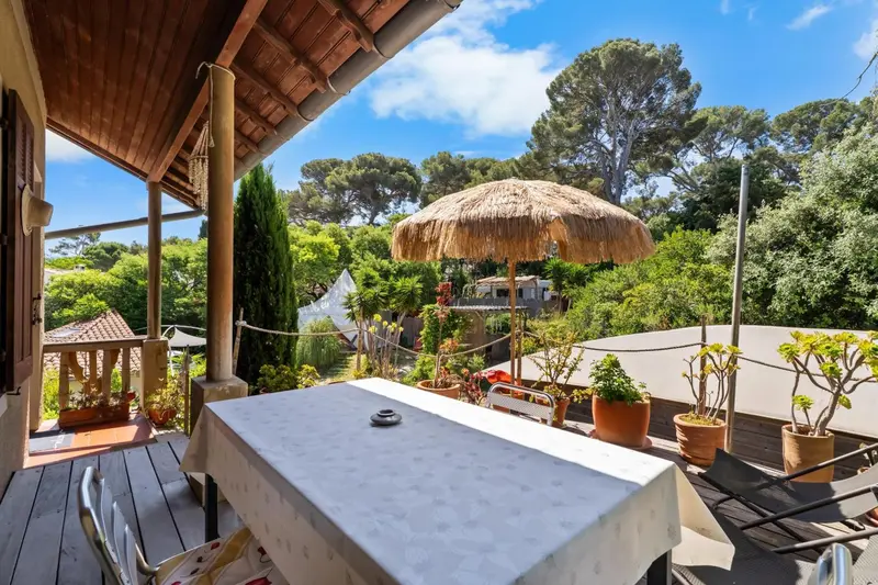 Une table recouverte d'une nappe blanche est mise en scène sur une terrasse ombragée.