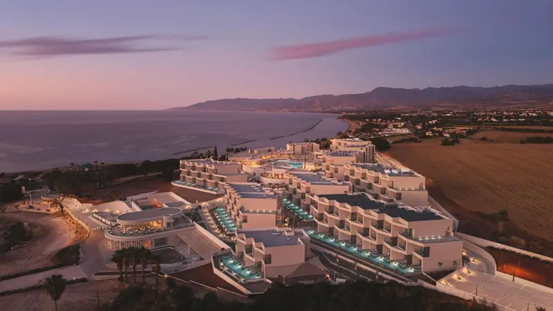 Vue aérienne d'un complexe hôtelier moderne au bord de la mer au coucher du soleil.
