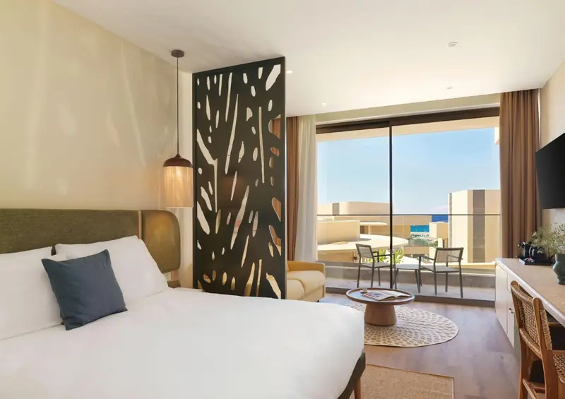 Une chambre lumineuse avec un grand lit et un accès à une terrasse.