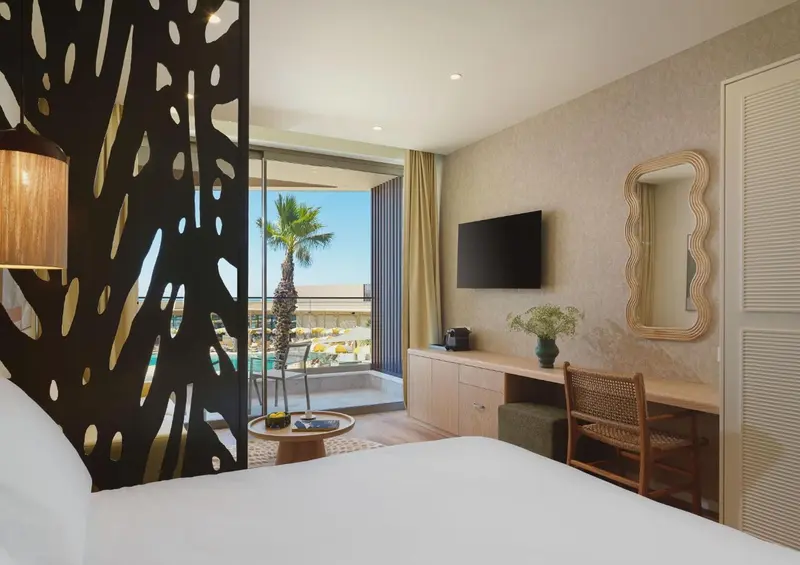 Une chambre lumineuse avec un lit blanc et une vue sur la mer.