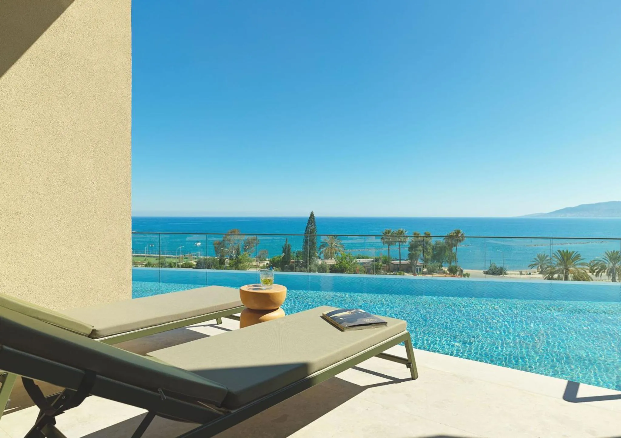 Deux transats se trouvent au bord d'une piscine à débordement avec vue sur la mer.