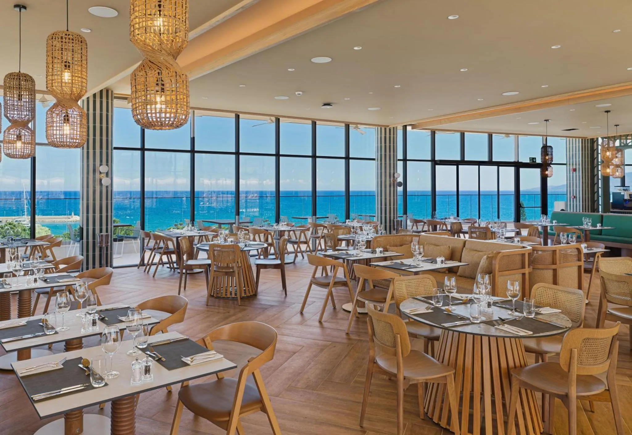 Une salle lumineuse avec de grandes baies vitrées donnant sur l'océan et des tables dressées pour le repas.