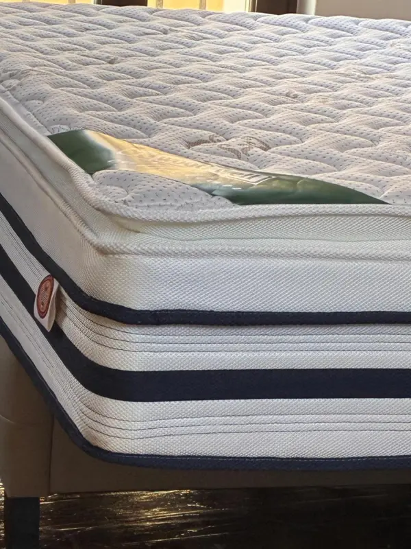 Un lit avec un matelas blanc et bleu est présenté dans une chambre.