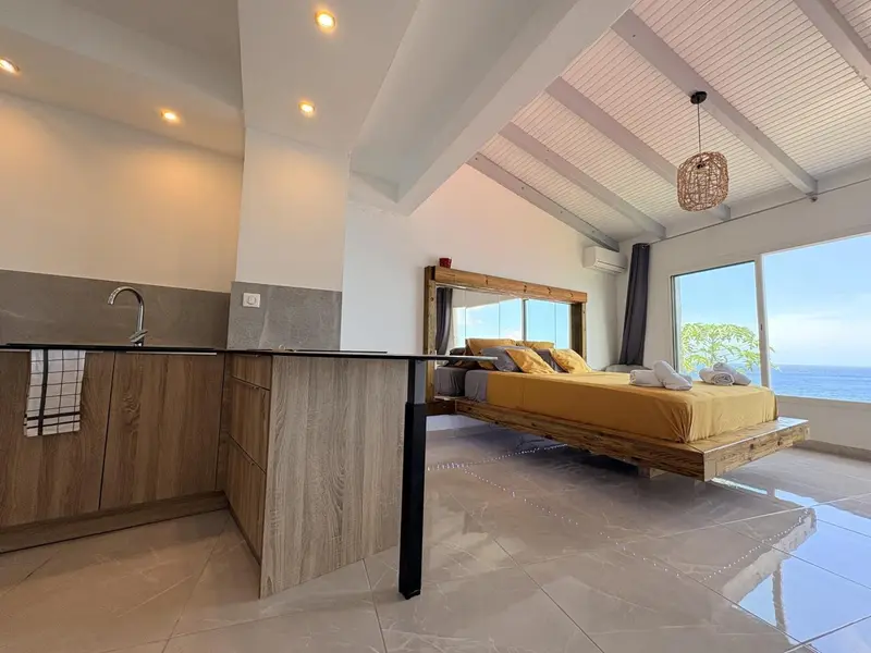 Une chambre lumineuse avec un lit et une kitchenette.