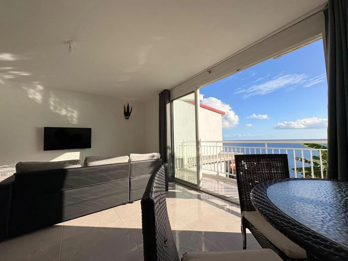 Un salon lumineux s'ouvre sur une terrasse avec vue sur la mer.