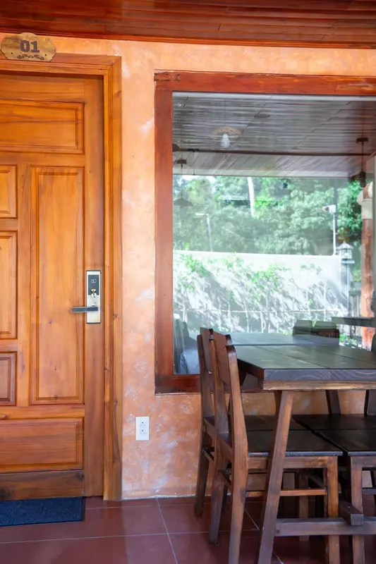 Une porte en bois s'ouvre sur un espace repas avec table et chaises.