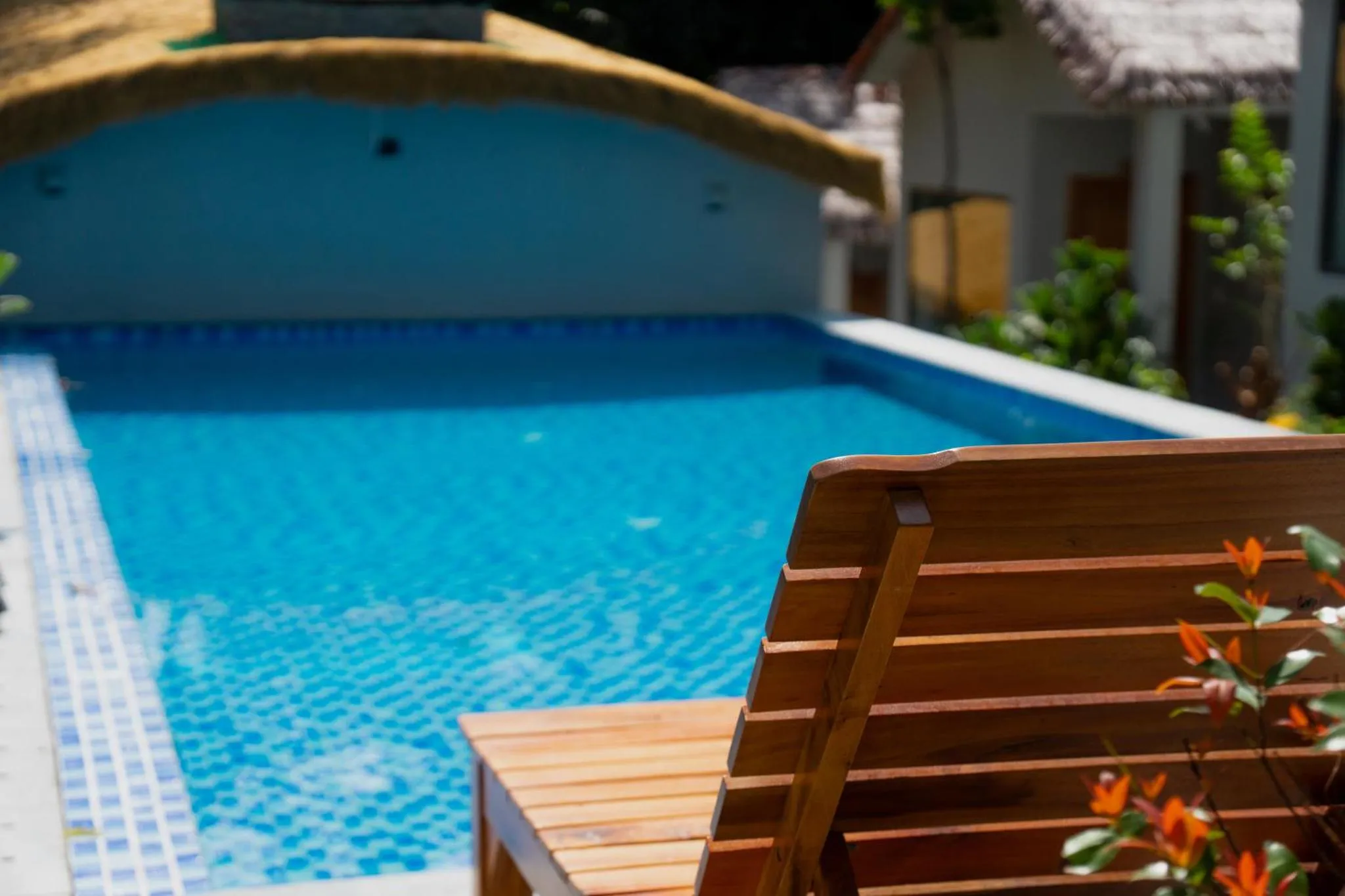 Une piscine turquoise bordée de chaises longues en bois.