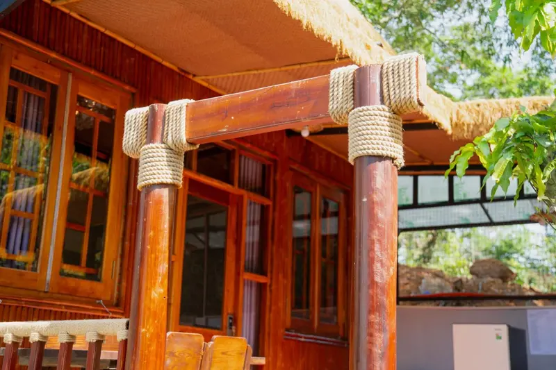 Terrasse en bois avec toit de chaume et mobilier d'extérieur.