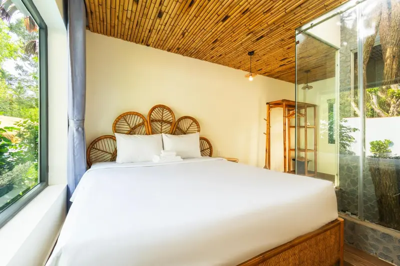 Une chambre lumineuse avec un grand lit et une décoration en rotin.
