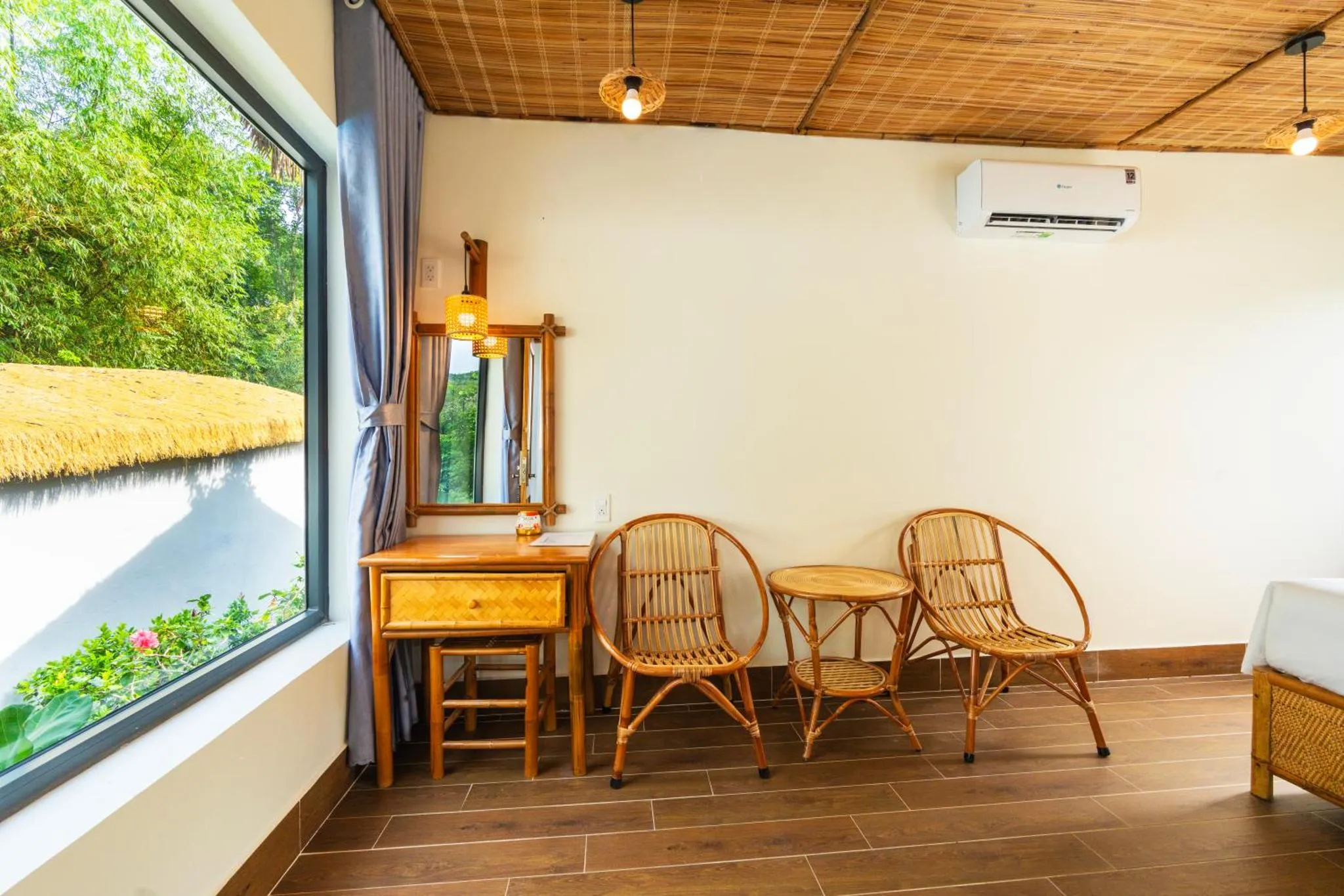 Espace de détente lumineux avec mobilier en rotin et vue sur la végétation.