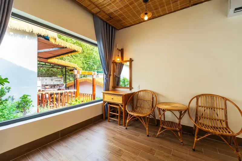 Une pièce lumineuse avec un coin salon en rotin et une vue sur une végétation luxuriante.