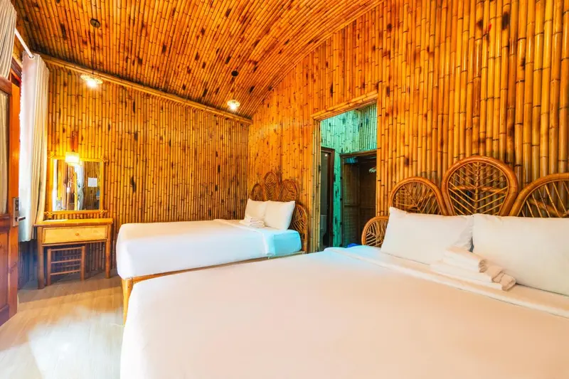 Chambre lumineuse avec deux lits et décoration en bambou.