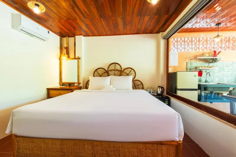 Une chambre lumineuse avec un lit double et un coin cuisine.
