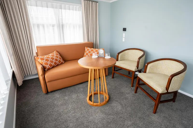 Un coin salon avec un canapé, une table ronde et deux fauteuils.