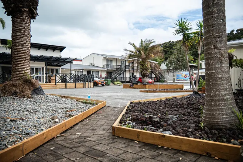 Allée pavée bordée de parterres de gravier mène à une cour d'établissement tropical.