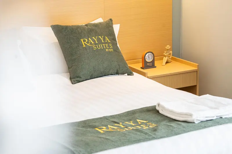 Un lit blanc est orné d'un coussin vert et d'une couverture verte.
