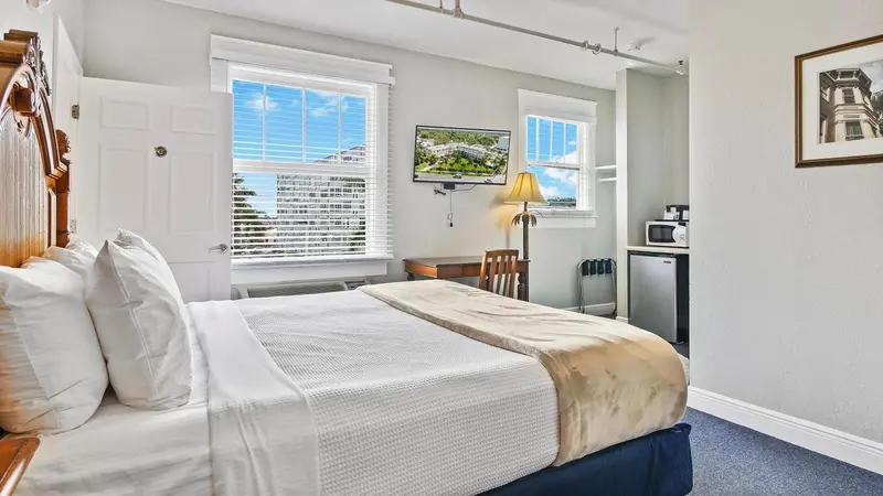 Une chambre lumineuse avec un lit fait et une vue sur la mer.