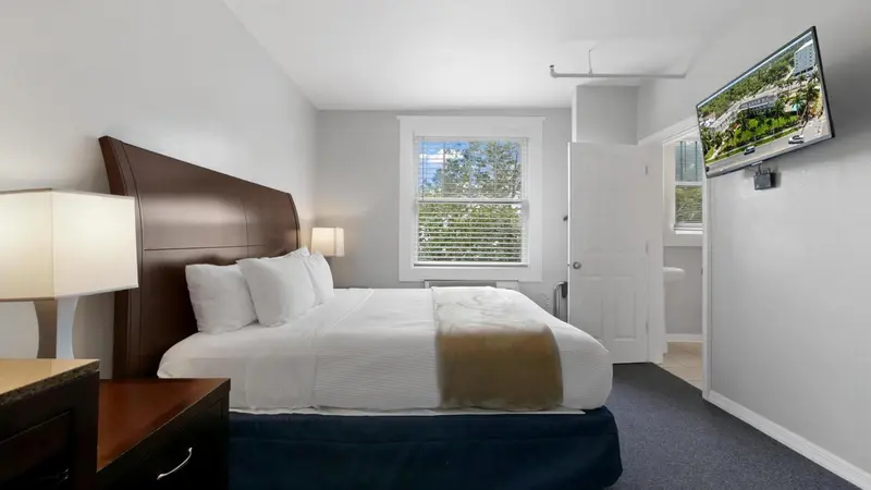 Une chambre avec un grand lit et une télévision murale.