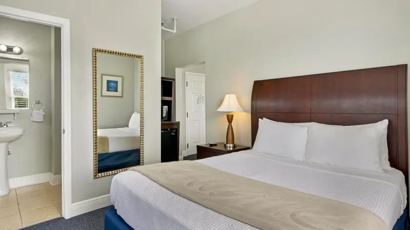 Une chambre lumineuse avec un grand lit et un miroir mural.