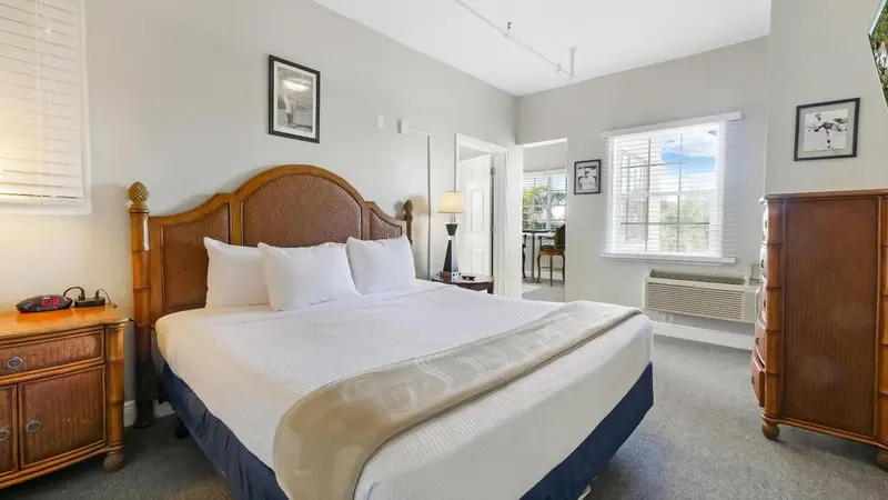 Une chambre lumineuse avec un grand lit et un bureau près de la fenêtre.