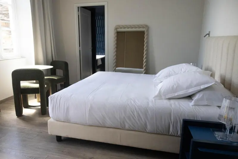 Une chambre lumineuse avec un grand lit et deux fauteuils.