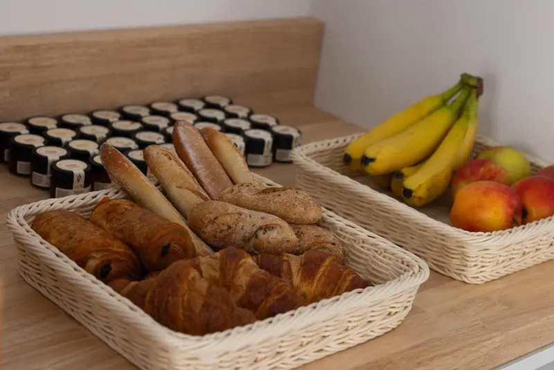 Assortiment de viennoiseries et de fruits frais présentés dans des paniers en osier.
